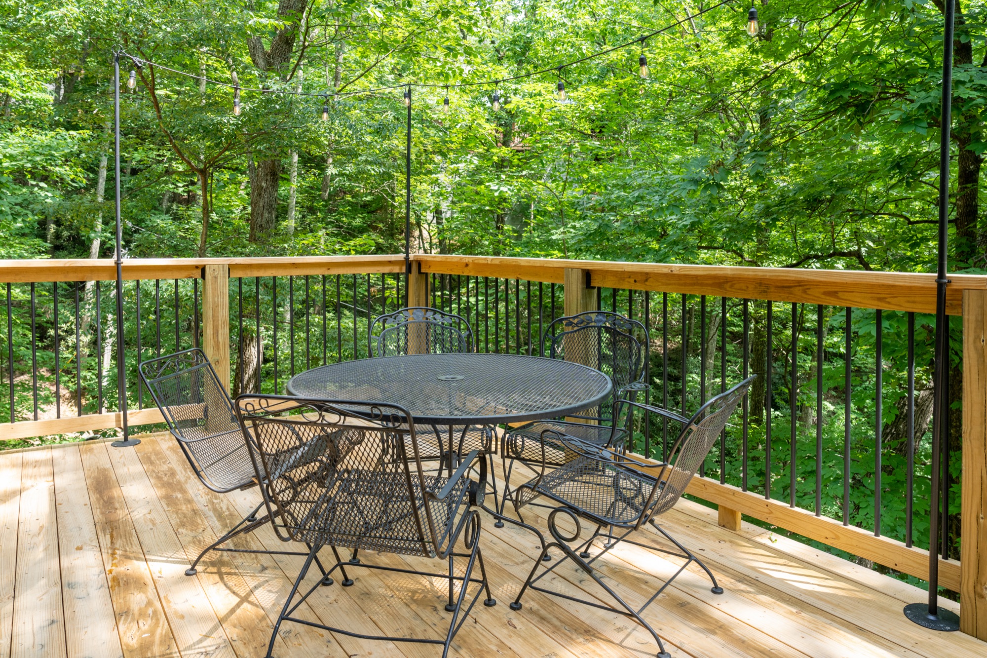 Patio table on Rustic Retreat's deck strung with string lights