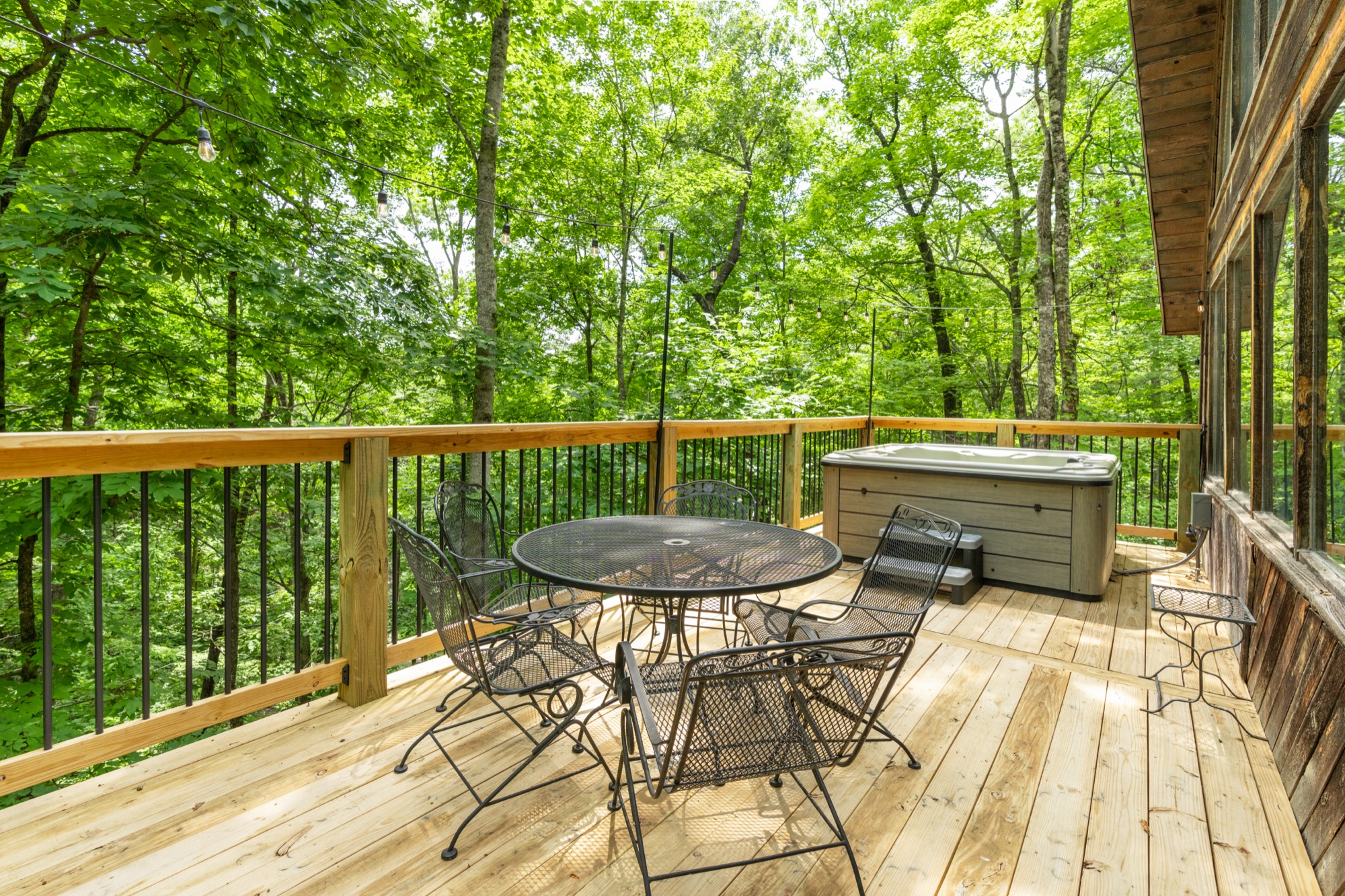 Rustic Retreat's deck by day with the hot tub and patio seating