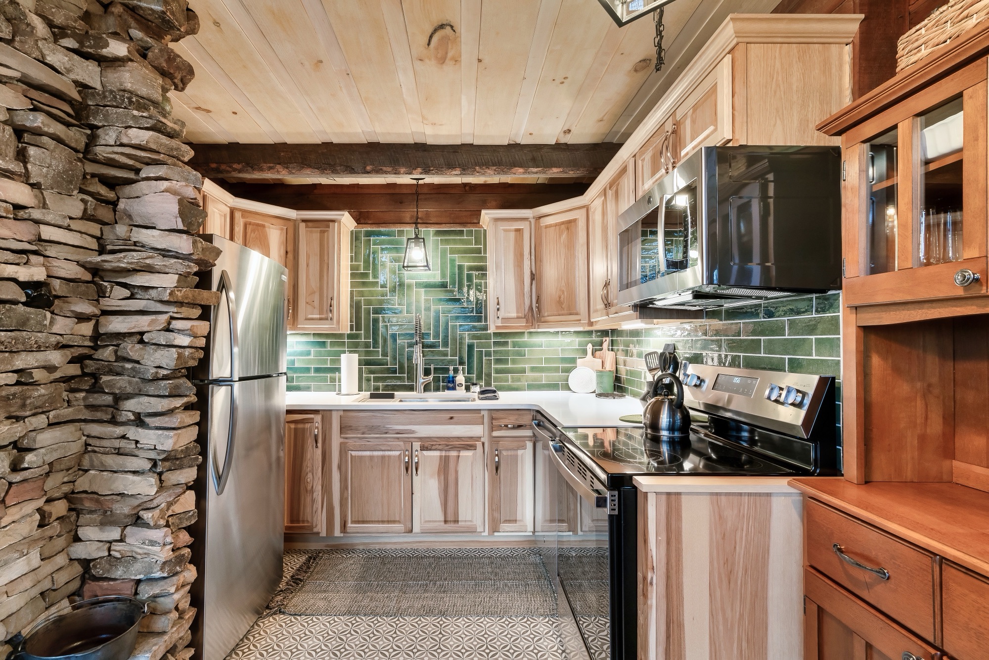 Rustic Retreat's kitchen with green tile backsplash and stainless appliances