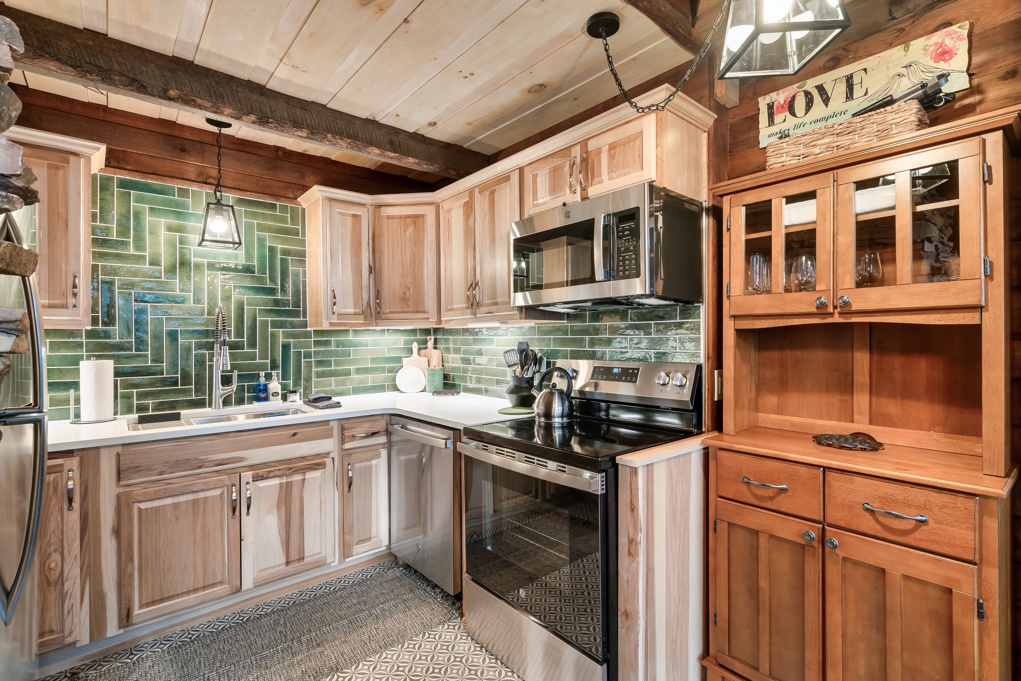 Rustic Retreat's kitchen corner with a herringbone green tile backsplash and a farmhouse hutch