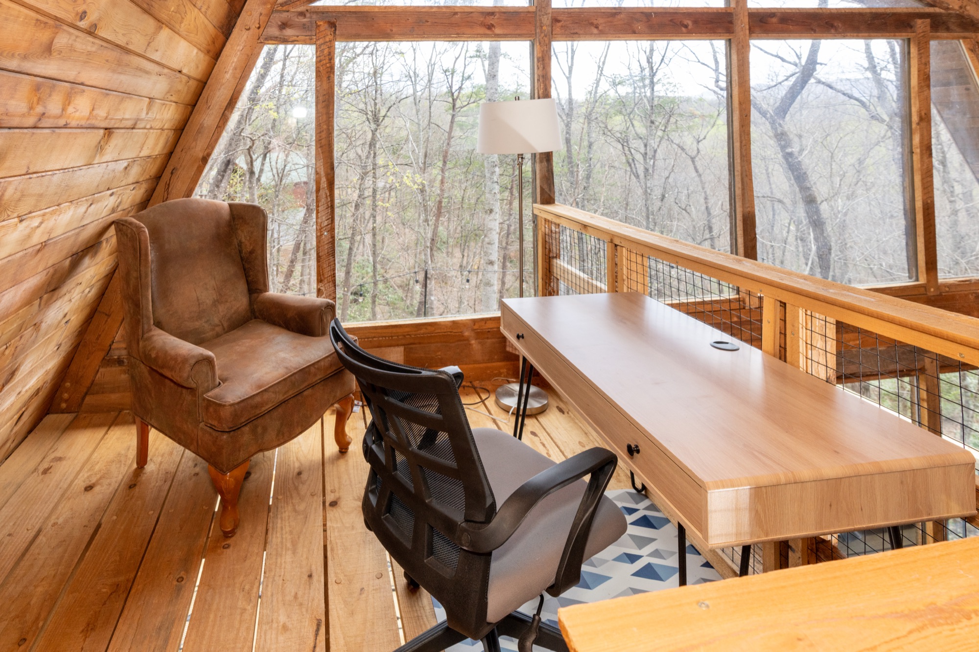 Loft office nook at Rustic Retreat with a desk and armchair overlooking the treetops